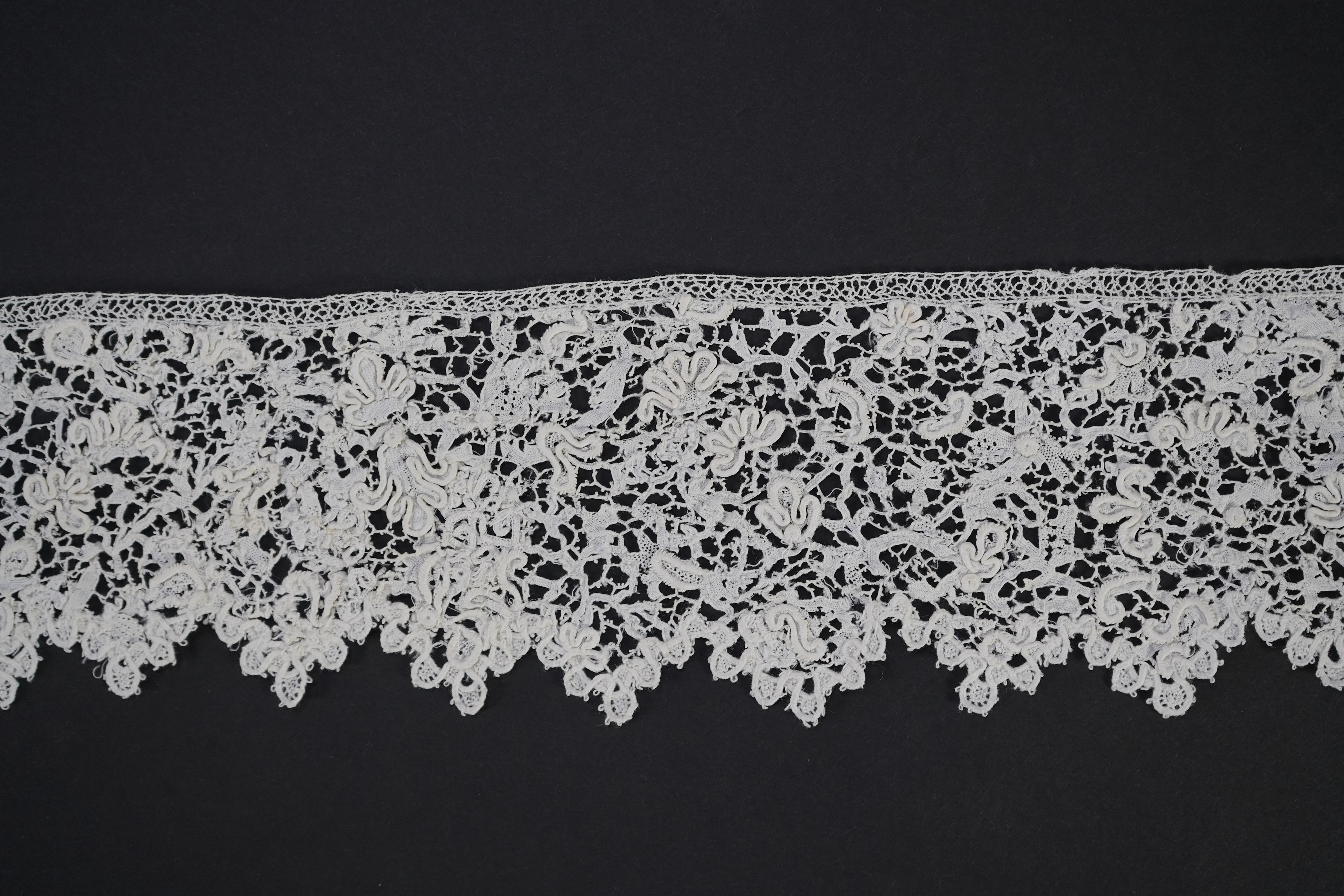 A late 17th century wide flounce of Point de France needle lace, together with a narrower flounce, both with raised elements of the design in the style of Point de Rose, but less so. This lace was very popular with the F